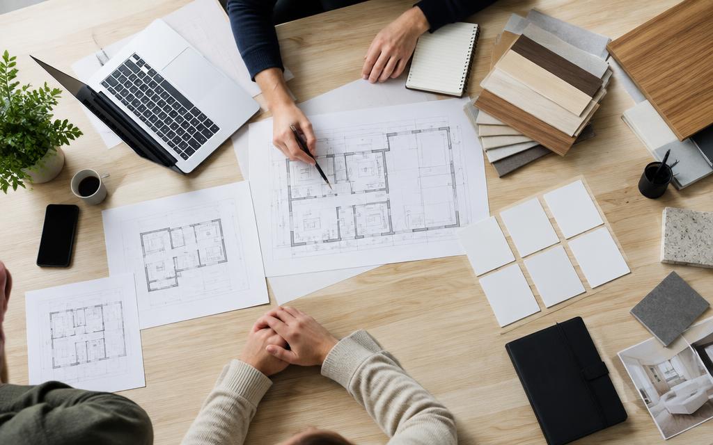 Construction recruitment planning table with drawings, laptop and material samples