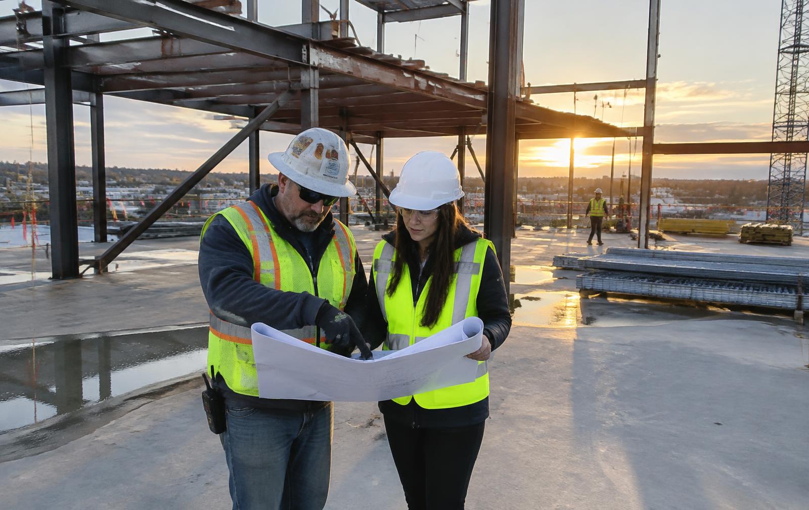 Construction superintendent and project manager reviewing drawings on a ground-up commercial construction site